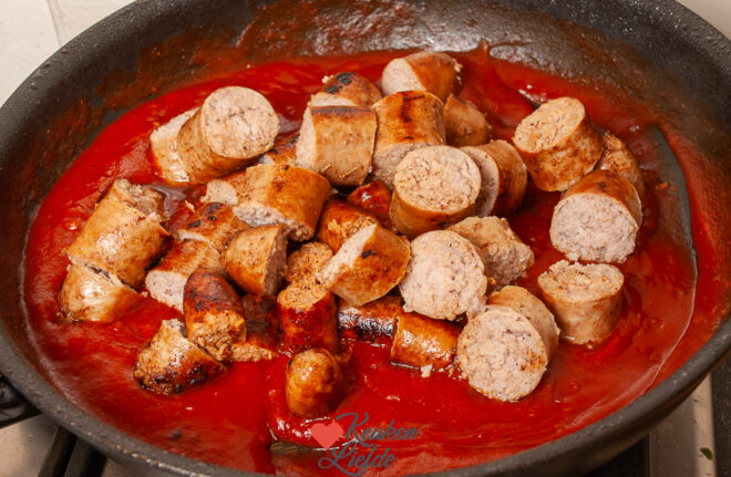 Roer de worst door de saus