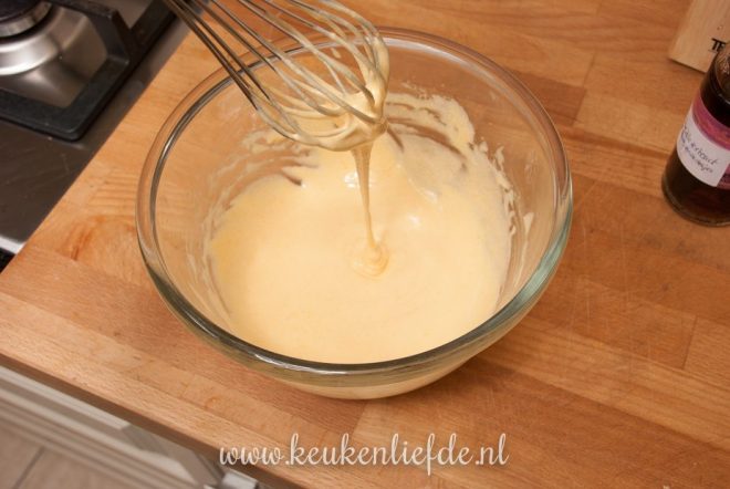 Klop de eidooiers en suiker au bain-marie tot een dikke, gele crème