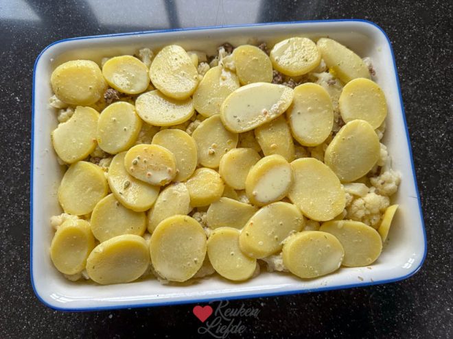 Maag laagjes in de ovenschaal en bedek met saus en kaas